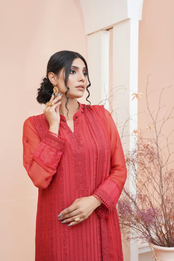 Woman in elegant traditional red dress posing indoors with an artistic touch.