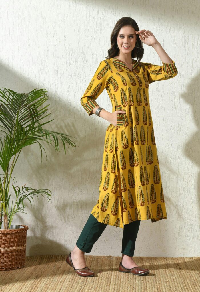 Woman posing in stylish Ajrakh printed kurta, showcasing ethnic fashion indoors.